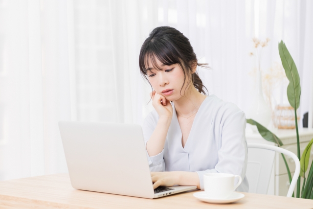 パソコンの前で悩んでいる女性の写真。